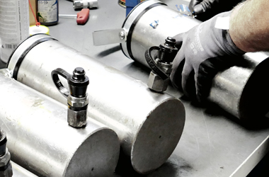 Erfahren Sie mehr über unseren schnellen Reparatur- und Wartungsservice Nahaufnahme der Wartung und Instandsetzung von silbernen Hydraulikzylindern in der Werkstatt
